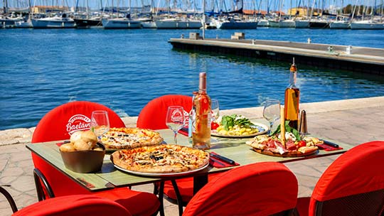 Table en terrasse de la Pizzeria Gaetano au port de Toulon avec pizzas et vue sur la marina