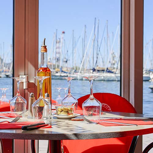 Table dressée dans la salle de la Pizzeria Gaetano au port de Toulon avec vue sur la marina et les voiliers